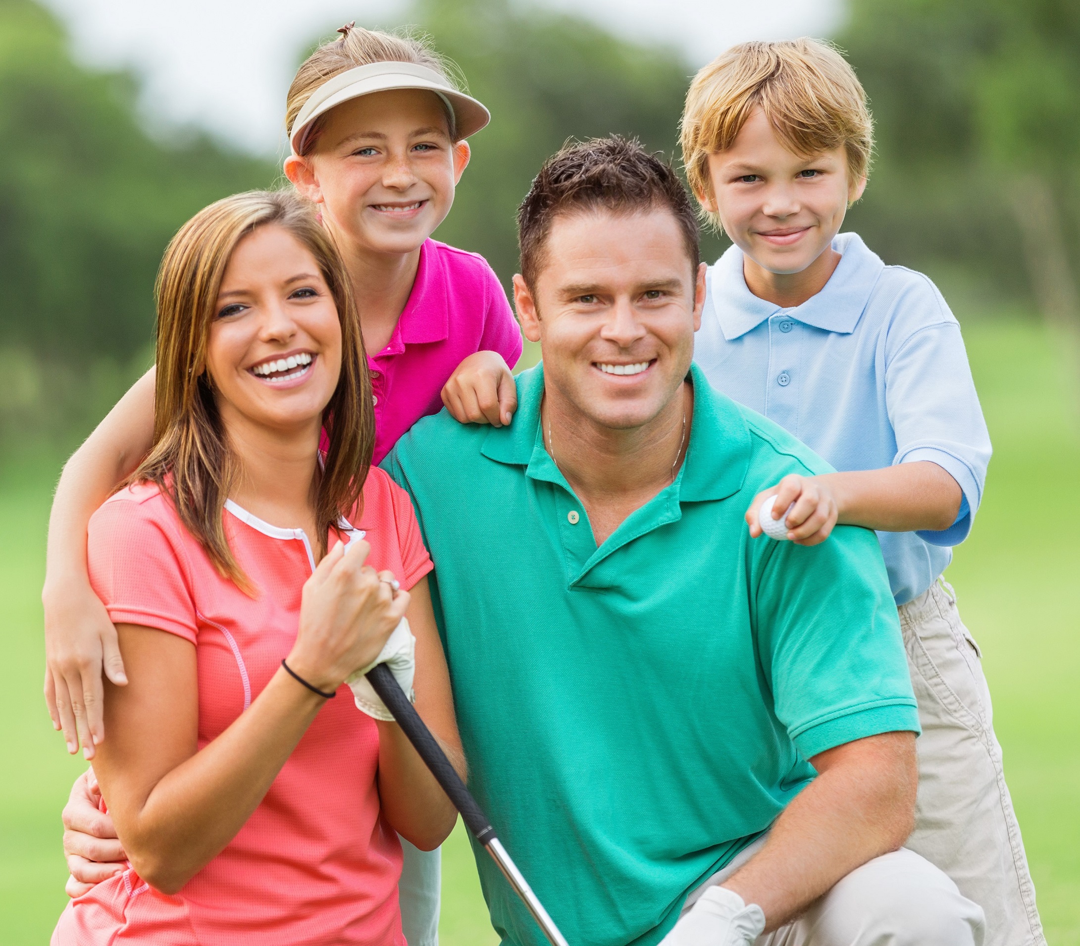 Happy family playing golf together on green course.